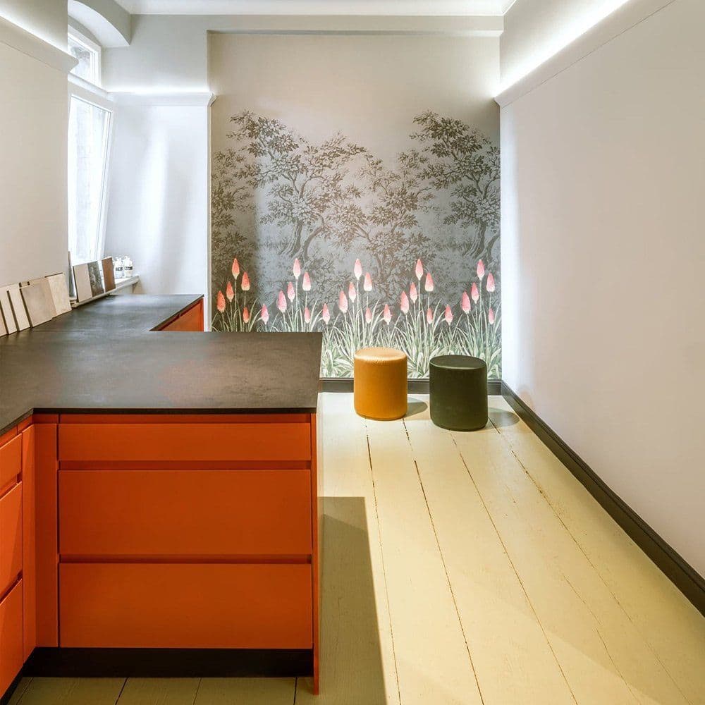 Raum mit Little-Greene-Tapete im Baummotiv, beleuchteter Wandleiste und orangefarbenem Küchenblock