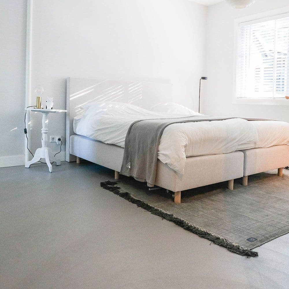 Schlafzimmer mit fugenlosem grauem Boden und hellem Bett