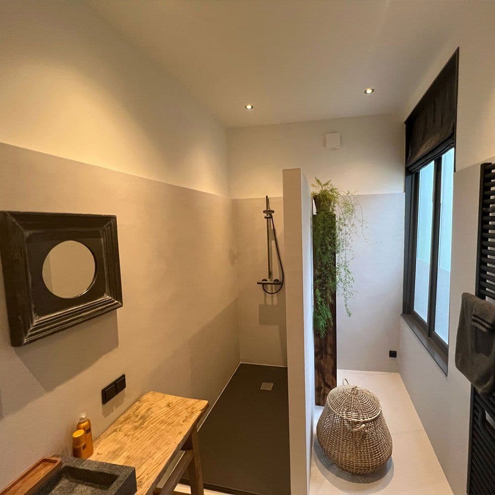 Fugenloses Bad in hellem Grau mit begehbarer Dusche und Holzdetails