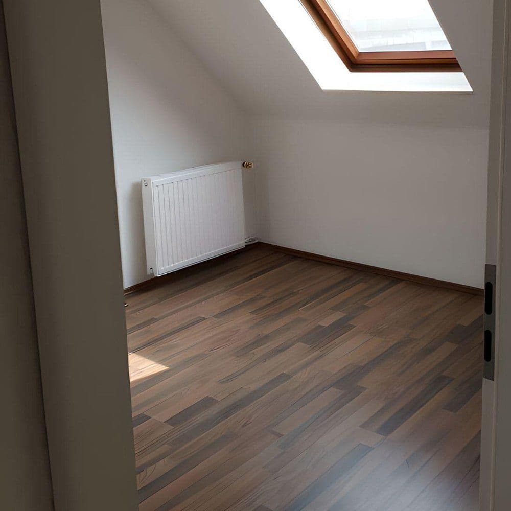 Dachgeschossraum mit Laminatboden in brauner Holzoptik und frisch gestrichenen Wänden