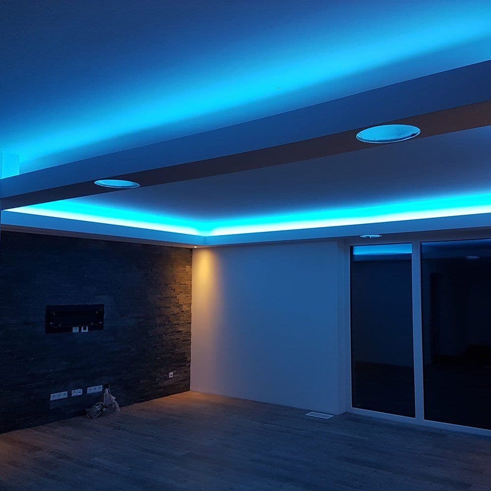 Wohnraum mit abgehängter Decke und blau leuchtender Lichtvoute am Abend