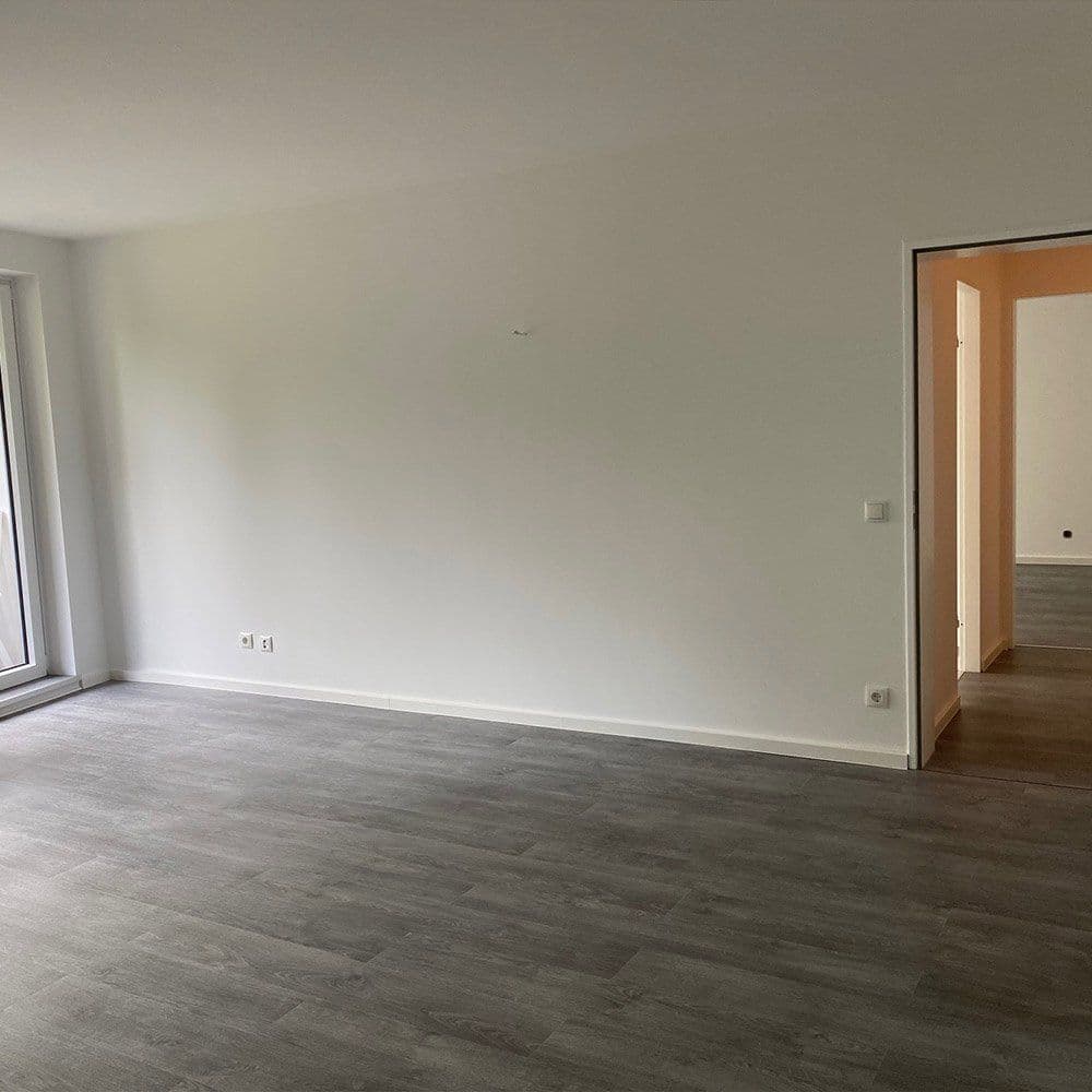 Leerer, renovierter Wohnraum mit grauem Rigid-Vinylboden und weiß gestrichenen Wänden